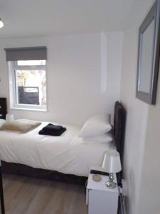 a bedroom with a white bed with a window at City Beach AirBnB Southend on Sea, in Southend-on-Sea