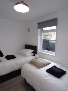 2 camas en una habitación con ventana en City Beach AirBnB Southend on Sea,, en Southend-on-Sea