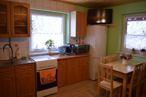 a kitchen with wooden cabinets and a table and a refrigerator at Domek pod Soszowem in Wisła