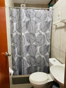 a bathroom with a shower curtain with a toilet at Sunset Hostel Airport in Lima