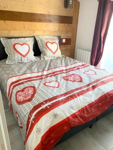 a bed with a red and white quilt with hearts on it at Veyrier-du-Lac ANNECY 60 m2 4-6 pers proche plage 1Garage Terrasse vue lac in Veyrier-du-Lac