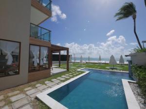 a house with a swimming pool next to the ocean at Pousada Ecos Beach in Porto De Galinhas
