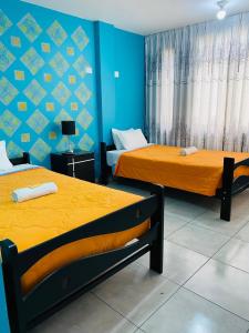2 camas en una habitación con paredes azules en Sunset Hostel Airport, en Lima