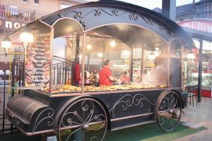 a man cooking food in a food cart in a market at Посейдон-3, отель in Vityazevo