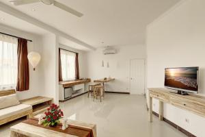 Nipuri Resort and Villas Seminyak by Kamara في سمينياك: غرفة معيشة مع أريكة وتلفزيون على الحائط