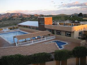 un complejo con piscina y montañas de fondo en Hospedium Hotel Los Periquitos, en Fortuna