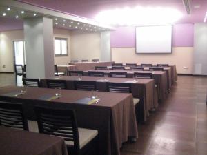 una sala de conferencias con mesas, sillas y una pantalla en Hospedium Hotel Los Periquitos, en Fortuna