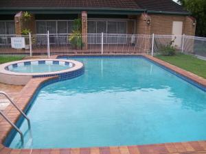 a swimming pool in a yard with blue water at Sun Plaza Motel - Mackay in Mackay