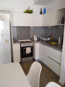 a small kitchen with white cabinets and a stove at Mirador 703 Palermo in Buenos Aires