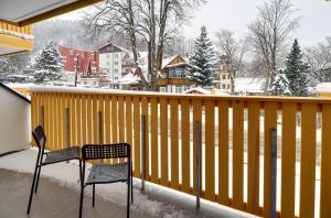 2 Stühle und ein Tisch auf einem Balkon mit Schnee in der Unterkunft Apartament Królewski w centrum in Karpacz