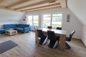 a living room with a table and a blue couch at Ferienhaus-Wiesengrund in Dranske