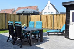 Una mesa y sillas con una sombrilla en un patio. en OK113 Vakantiewoning Zeeduinsepoort 14A met sauna, en Oostkapelle