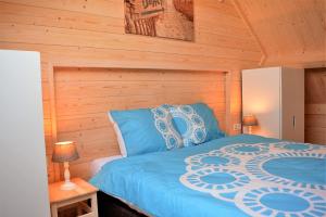 Un dormitorio con una cama azul con una pared de madera. en OK113 Vakantiewoning Zeeduinsepoort 14A met sauna, en Oostkapelle