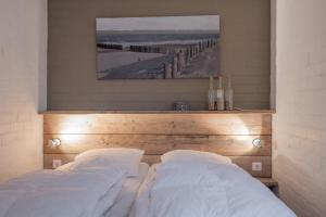 um quarto com 2 almofadas brancas e uma cabeceira em madeira em Kustverhuur, Park Schoneveld, Duinroos 123 em Breskens