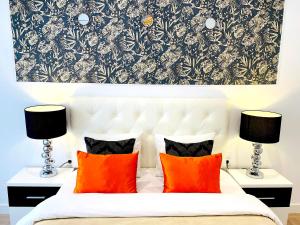 1 dormitorio con cama blanca y almohadas de color naranja en Palacio Apartments Madrid en Madrid