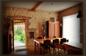 a dining room with a table and chairs and a brick wall at Chez Fifine in Mont-Saint-Éloi