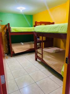 een kamer met 2 stapelbedden en een tegelvloer bij Sunset Hostel Airport in Lima