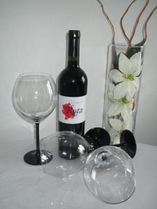 a bottle of wine and a glass and a vase with flowers at Apartment Rota in Zadar