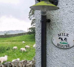 a sign on the side of a building with sheep in a field at Barcloy Milk House in Kirkcudbright