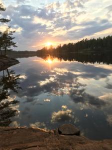 - une vue sur un lac au coucher du soleil avec des nuages dans l'eau dans l'établissement Björsjöås Vildmark - Small camping cabin close to nature, à Olofstorp
