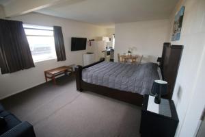 a bedroom with a bed and a table in it at Foreshore Motor Lodge in Petone