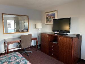 Habitación de hotel con escritorio y tocador con TV. en Travelodge by Wyndham Farmington Hwy 64, en Farmington