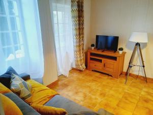 a living room with a couch and a television at gîtes de la petite suisse in Clécy