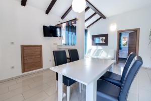 a dining room with a white table and blue chairs at Petra Apartment in Rab