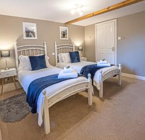 two beds in a bedroom with blue and white sheets at The Barley Mill in Elgin