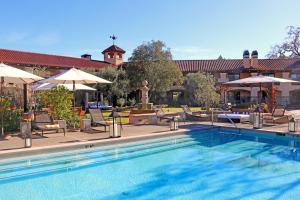 a swimming pool with chairs and umbrellas next to a building at Napa Valley Lodge in Yountville