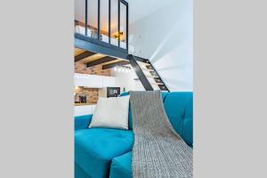 un sofá azul en una sala de estar con una escalera en L'Industriel - Appart'Hôtel SPA - Clim - Melina & Alfred Agen, en Agen