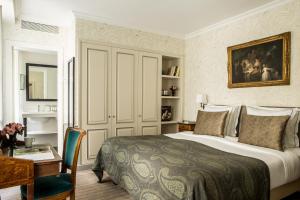 a bedroom with a large bed and a desk and a table at Hôtel des Saints Pères - Esprit de France in Paris