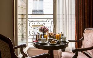 Hôtel des Saints Pères - Esprit de France في باريس: طاولة عليها طعام أمام النافذة