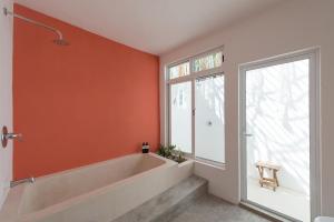 een oranje badkamer met een bad en een raam bij Casa Neem in Cancun
