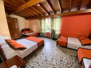 una camera da letto con due letti e una parete rossa di Hotel Tequendama a Pereira
