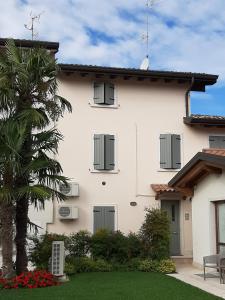 a white house with a palm tree and a yard at Corte Mantovani - Appartamenti in Colà di Lazise
