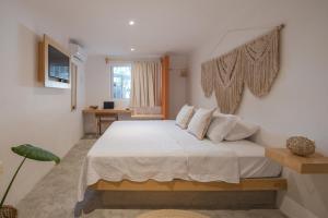 een slaapkamer met een bed met witte lakens en een raam bij Casa Neem in Cancun