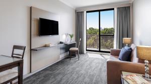 Oaks Sydney North Ryde Suites في سيدني: غرفة معيشة مع أريكة وتلفزيون بشاشة مسطحة