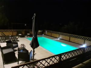 Gorica的住宿－Spacious apartment with views of the vineyards，夜间游泳池,配有椅子和遮阳伞
