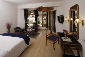 Schlafzimmer mit einem Bett, einem Tisch und Stühlen in der Unterkunft Manuallaya The Resort & Spa in Manali