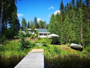 a house with a dock and a boat on the water at Lakeside cottage Metsäranta Savonranta in Savonranta