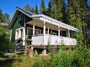 una pequeña casa verde con porche y flores en Lakeside cottage Metsäranta Savonranta, en Savonranta