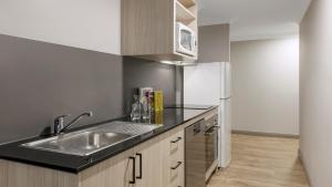 a kitchen with a sink and a refrigerator at Oaks Sydney North Ryde Suites in Sydney