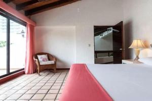 a bedroom with a bed and a chair and a window at Cancún Villa Mamey con acceso a Playa in Cancún