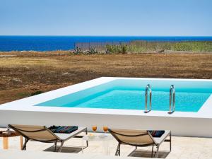 a swimming pool with two faucets and chairs and the ocean at Belvilla by OYO Capo Passero Dieci in Portopalo