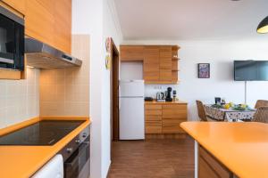 a kitchen with a white refrigerator and wooden cabinets at *AlgarvianStudio-Vilamoura City Centre* in Vilamoura