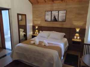 a bedroom with a bed with two towels on it at Pousada Alto dos Pinheiros in Monte Verde