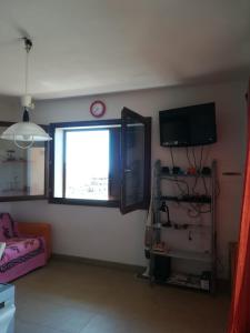 ein Wohnzimmer mit einem TV und einem Fenster in der Unterkunft Castelsardo,Lu bagnu in Castelsardo