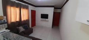 Una sala de estar con un sofá y un televisor. en prx à praia com piscina, en Mongaguá