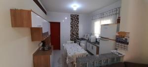 Una pequeña cocina con una mesa y un refrigerador. en prx à praia com piscina, en Mongaguá